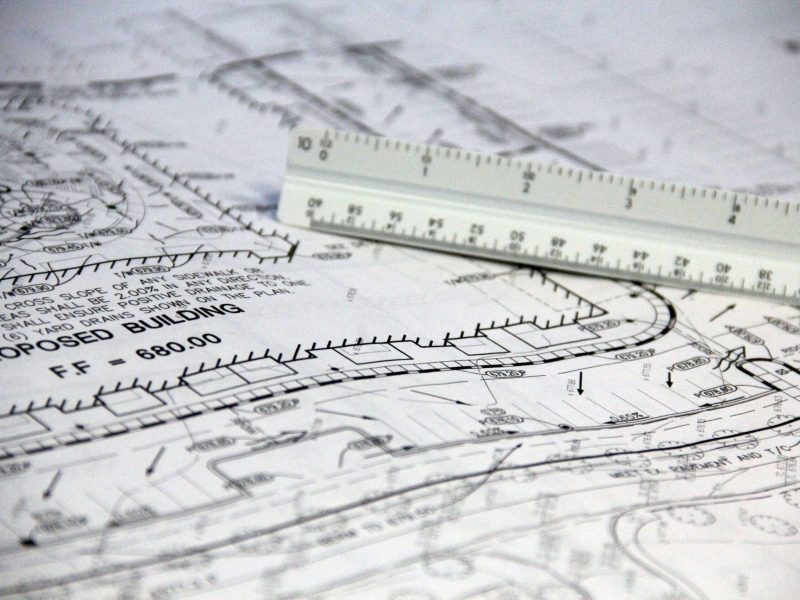 Detailed close-up of architectural blueprints with scale ruler, showing building plans and measurements.