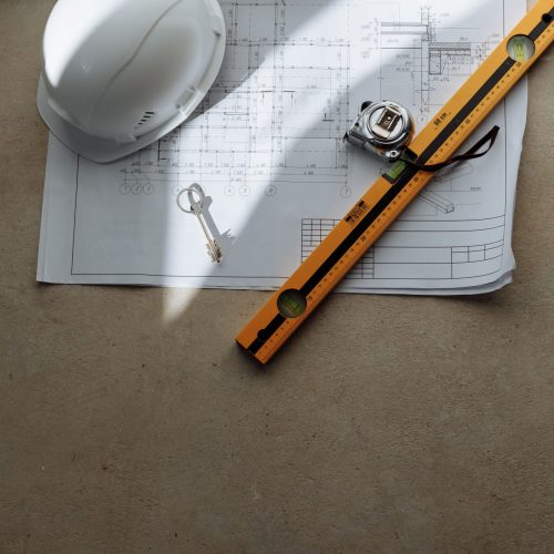 Top view of architectural blueprint with helmet and tools on table, ideal for construction theme.